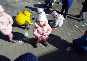 Dzieci malują kolorowymi kredami płyty chodnika